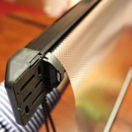 Pince en métal noir à fentes fixée sur un bord de tissu rayé sur un fond orange chaud