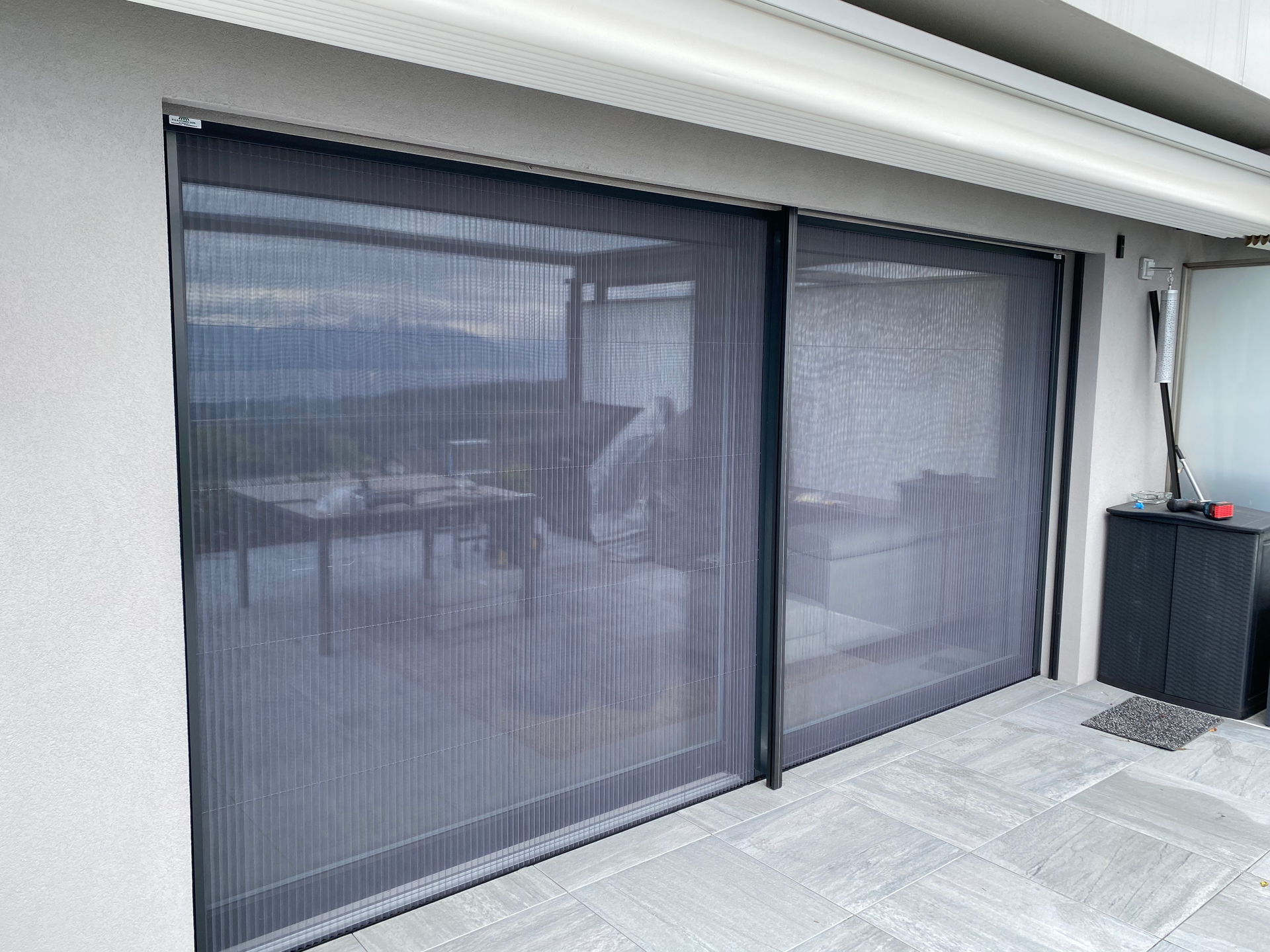 Portes coulissantes en verre avec stores occultants foncés sur un balcon ou une terrasse.