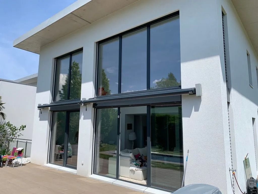 Extérieur de maison blanche moderne avec de grandes fenêtres du sol au plafond et des portes coulissantes en verre