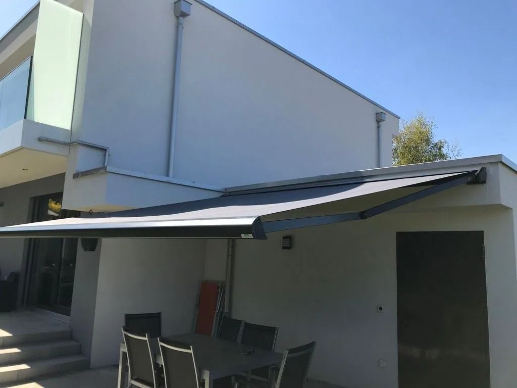 Extérieur moderne d'un bâtiment avec une terrasse couverte, une table et des chaises d'extérieur.