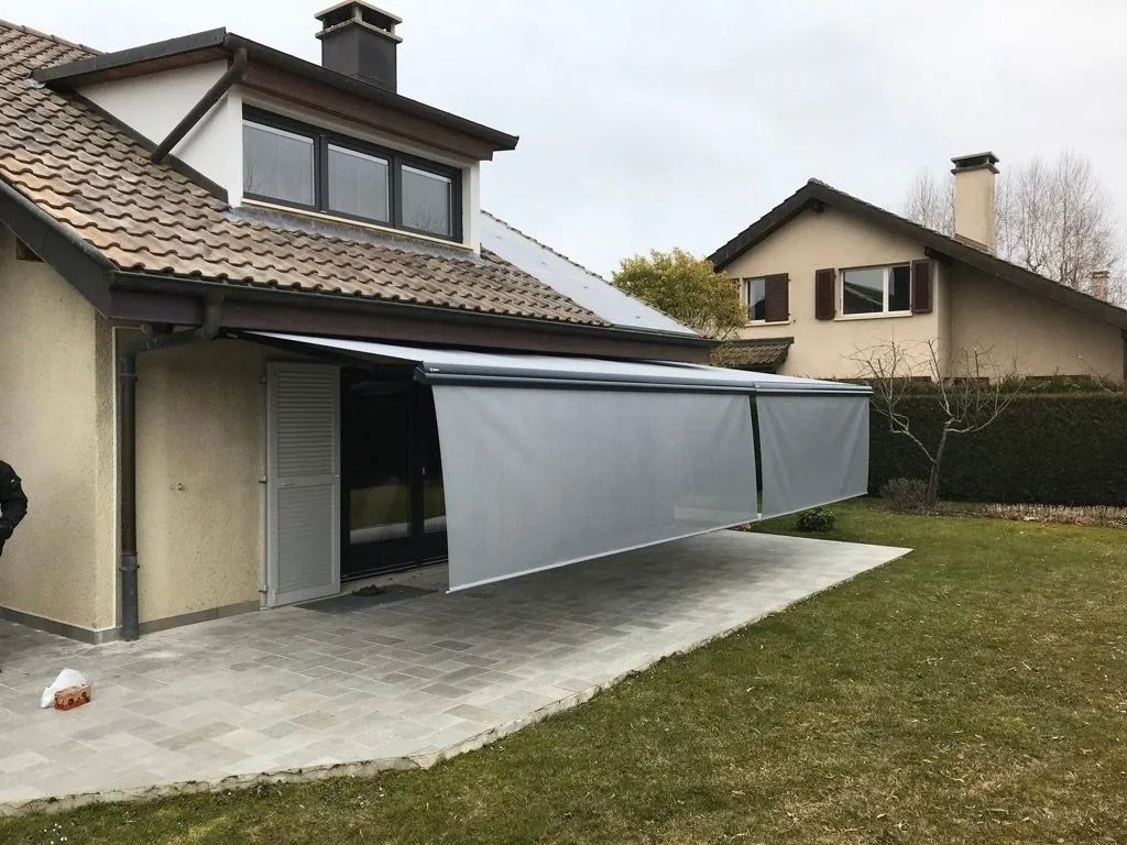 Un auvent de patio s'étend le long d'une maison, couvrant la terrasse arrière et la porte vitrée.