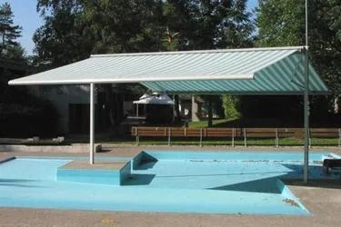 Piscine extérieure vide avec bassin d'eau bleue et structure d'ombrage au toit vert