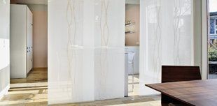 Intérieur de bureau moderne avec des rideaux de séparation blancs, une table en bois et une lumière naturelle abondante.
