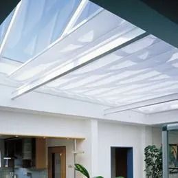 Pièce moderne avec un grand puits de lumière, des poutres blanches au plafond et une belle luminosité naturelle.