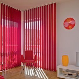 Chambre moderne avec stores verticaux rouges, chaise rouge et étagères blanches à la décoration colorée