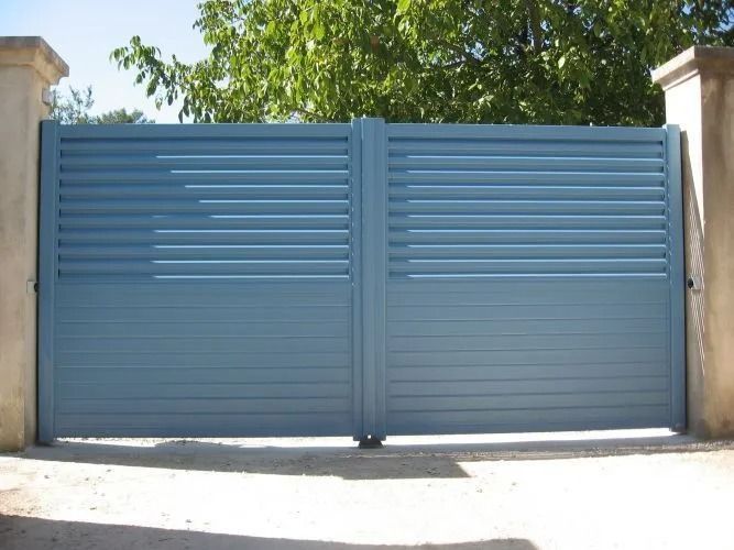 Portail double métallique bleu fermé à l'entrée d'une allée