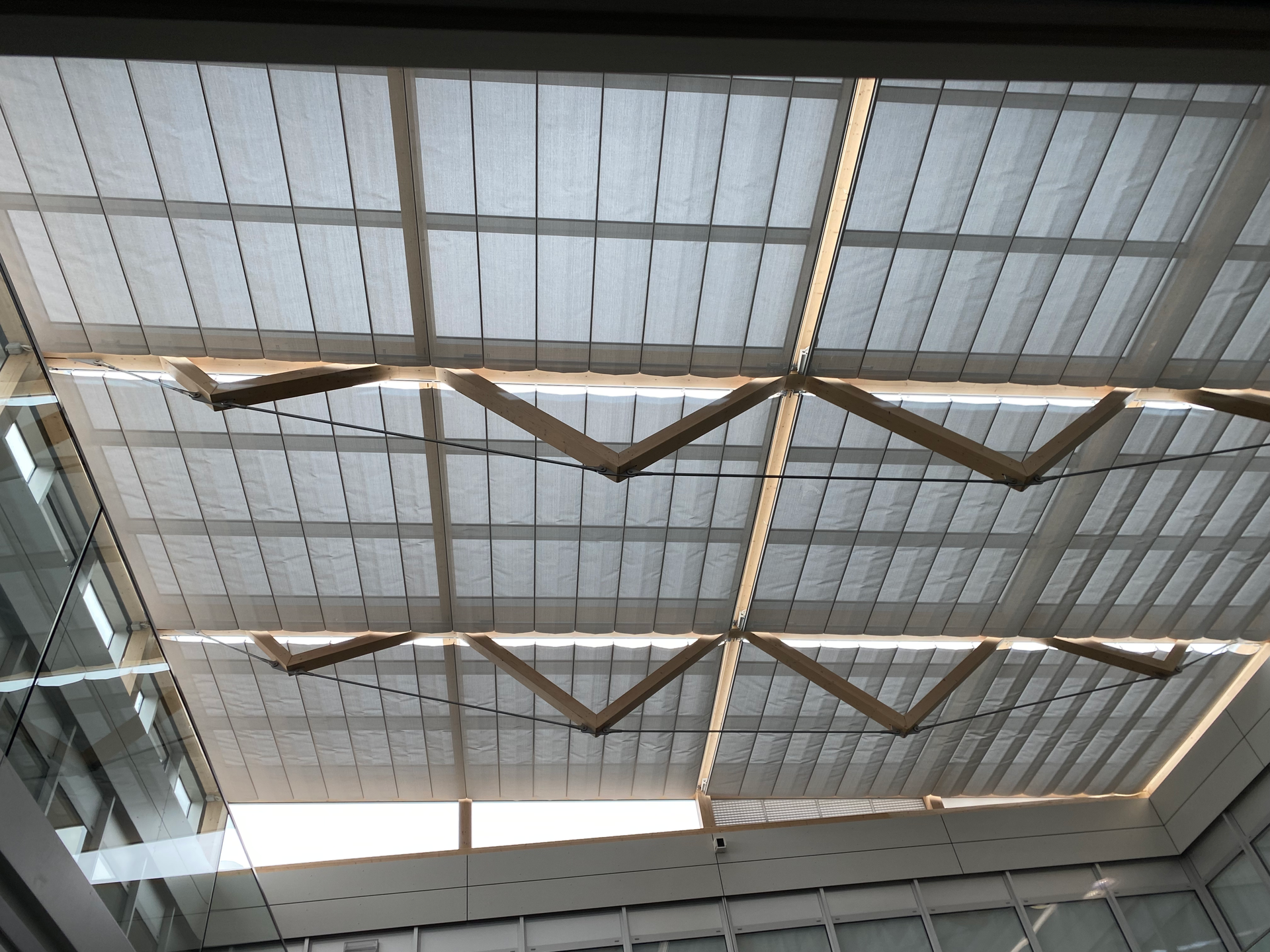 Plafond industriel avec toiture en tôle ondulée, poutres et panneaux décoratifs suspendus en zigzag