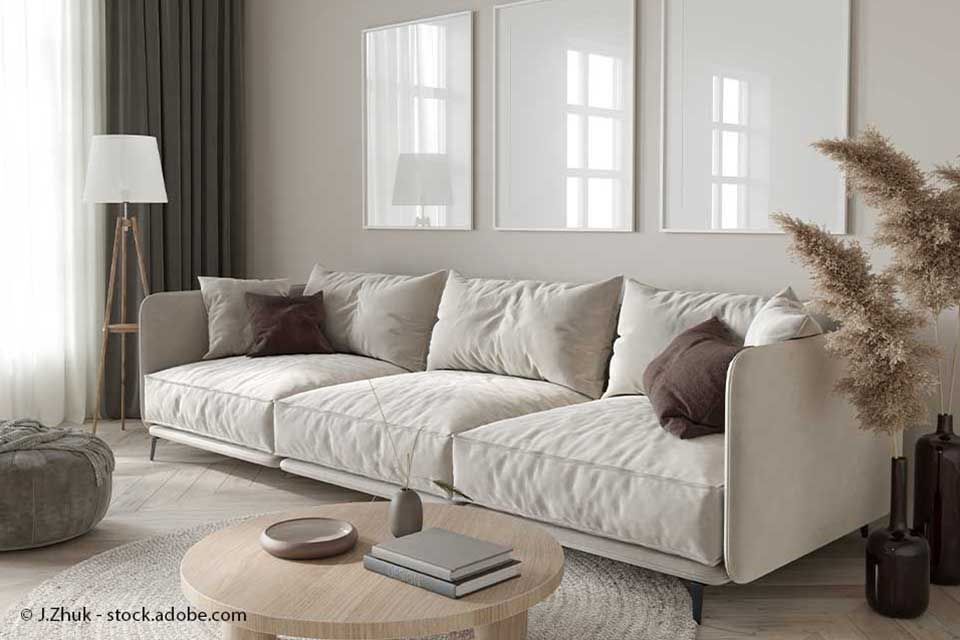 Wohnzimmer in neutralen Tönen; hellbeiges Sofa, runder Couchtisch, gerahmte Kunst.
