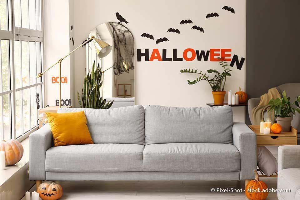 Für Halloween dekoriertes Wohnzimmer mit Kürbissen, Fledermäusen und dem Wort „Halloween“.