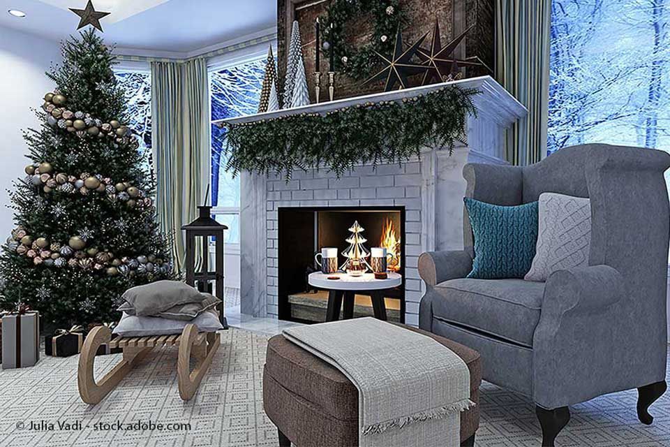 Gemütliches Weihnachtswohnzimmer mit Baum, Kamin, Sessel und verschneitem Fensterblick.