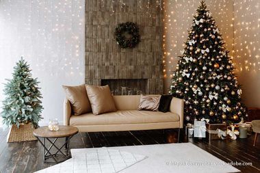 Gemütliches, weihnachtlich dekoriertes Wohnzimmer mit zwei Bäumen, Sofa, Kamin und Lichterketten.