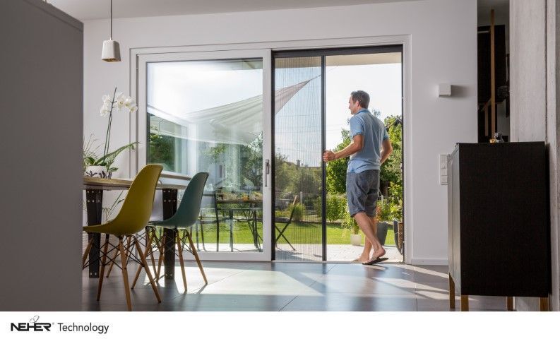 Mann öffnet Fliegengittertür, Blick in den Garten. Esszimmer mit Tisch und Stühlen.