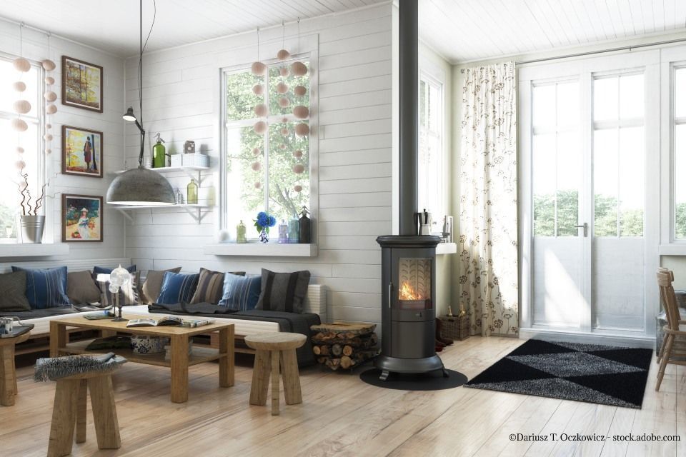 Gemütliches Wohnzimmer mit Holzofen, Holzmöbeln und einem hellen Fenster mit Blick ins Grüne.