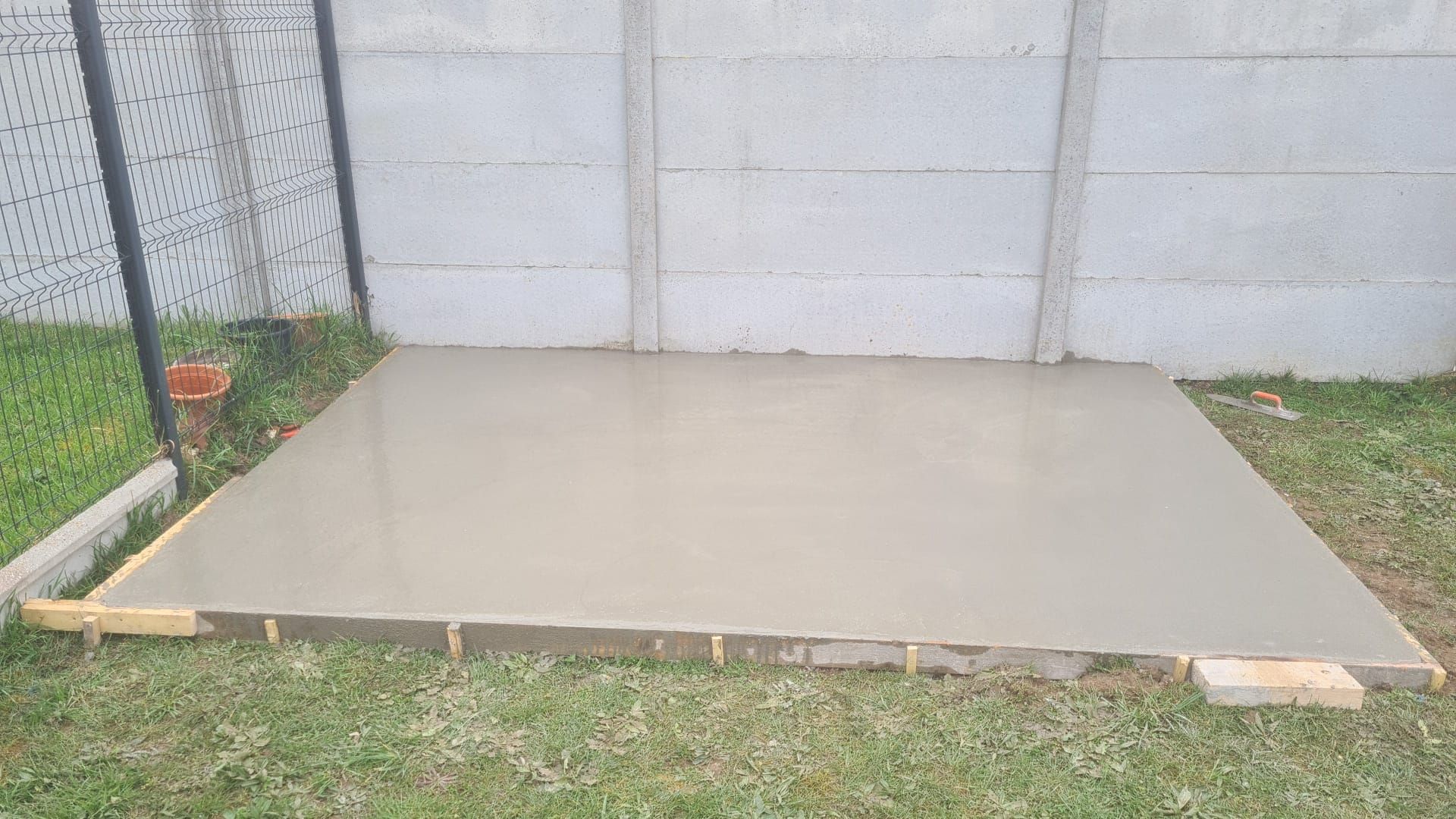 Dalle de béton fraîche jouxtant une clôture en grillage