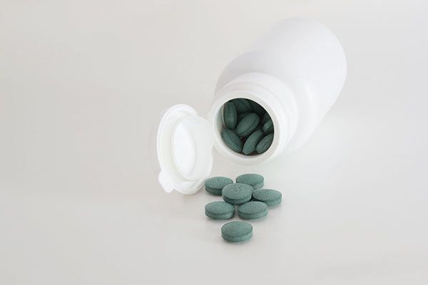 Un frasco de pastillas verdes se está derramando de él.