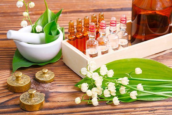 Flores de lirio de los valles, mortero y botellas de aceites esenciales sobre una mesa de madera.