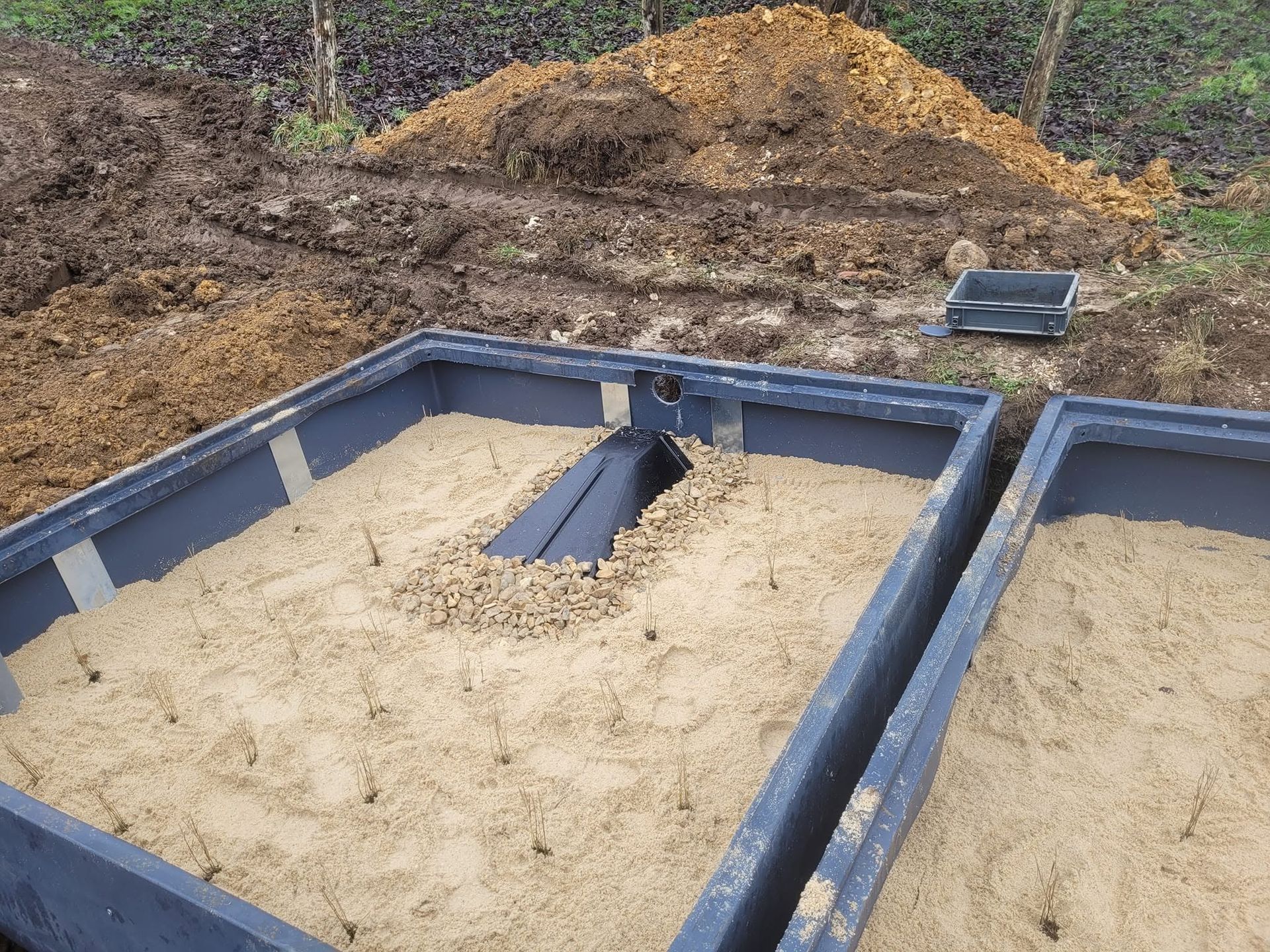 Ossature bleue de fondation avec du sable de remblai sur un chantier, avec des tas de terre en arrière-plan