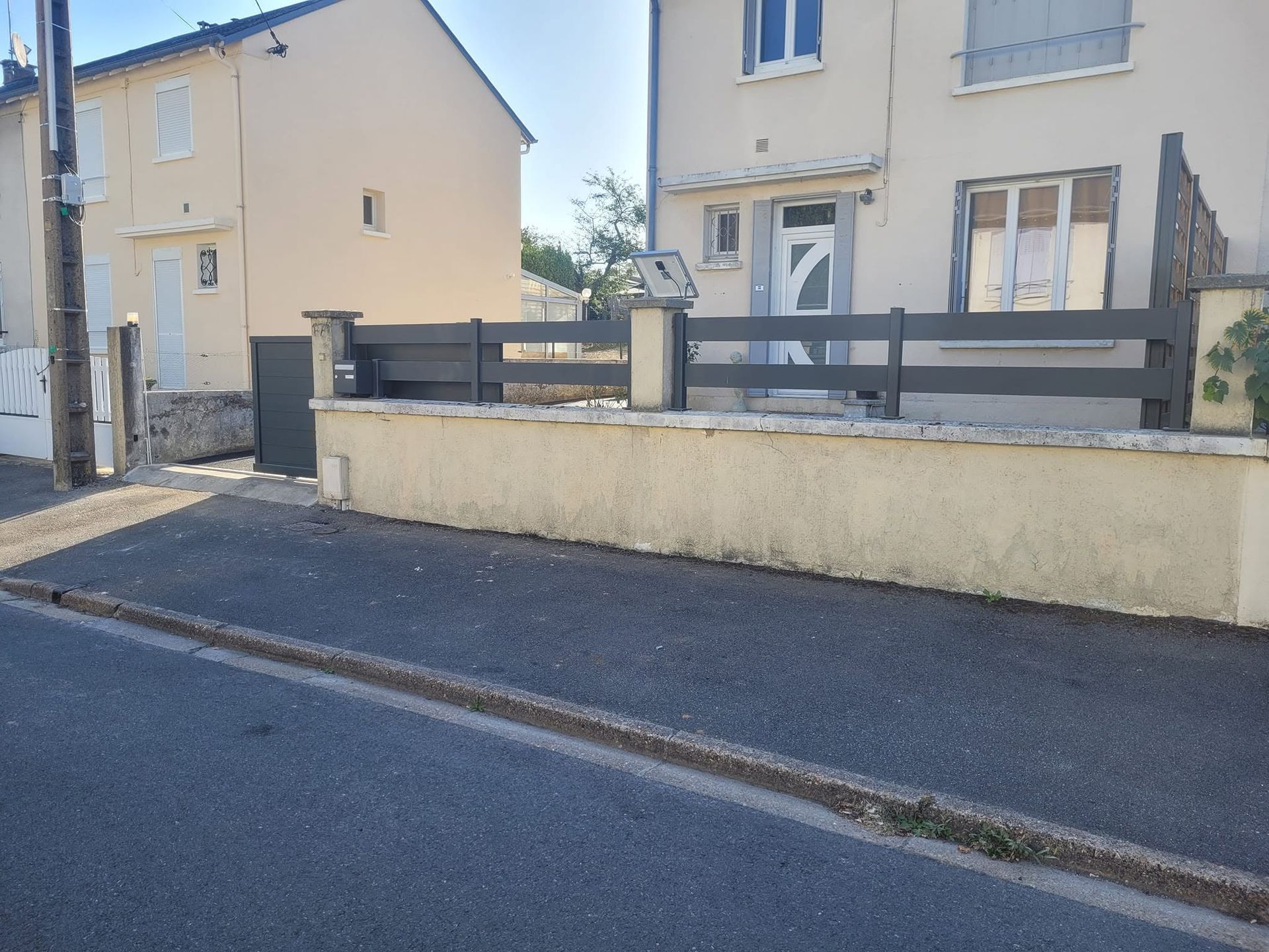 Des maisons d’habitation derrière un muret, le long d’une rue calme par une journée ensoleillée