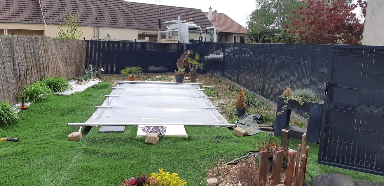 Arrière-cour avec une piscine rectangulaire couverte, une pelouse verdoyante et un espace jardin clôturé