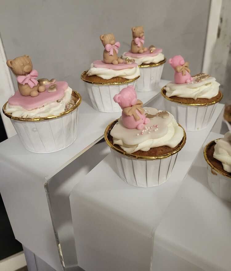 Un montón de pastelitos con ositos de peluche encima de ellos sobre una mesa.