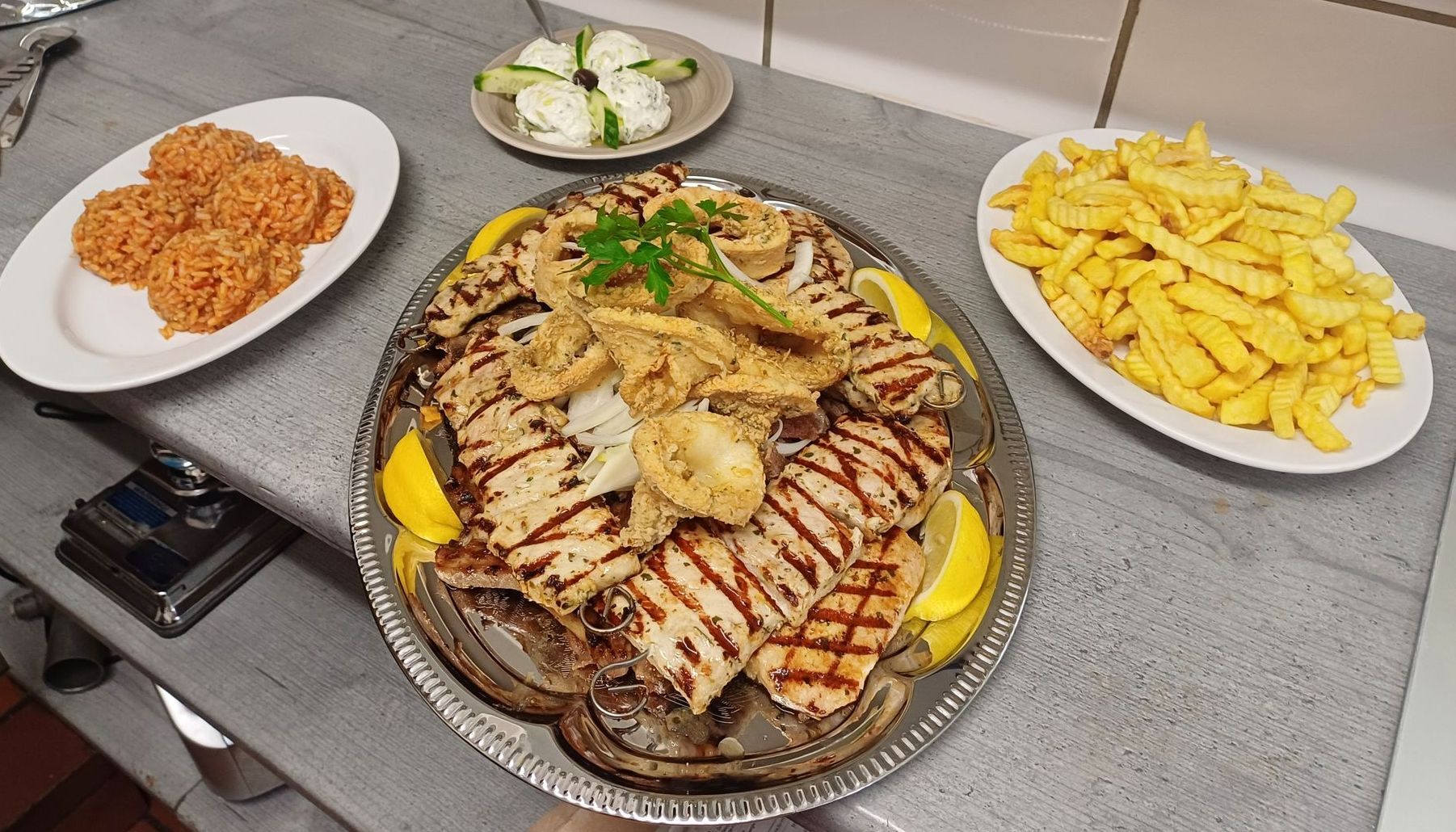 Bauernscheuer Gaststätte - Teller, Oktopusarm garniert mit Gurkenscheiben, Tomaten und Frischkäse