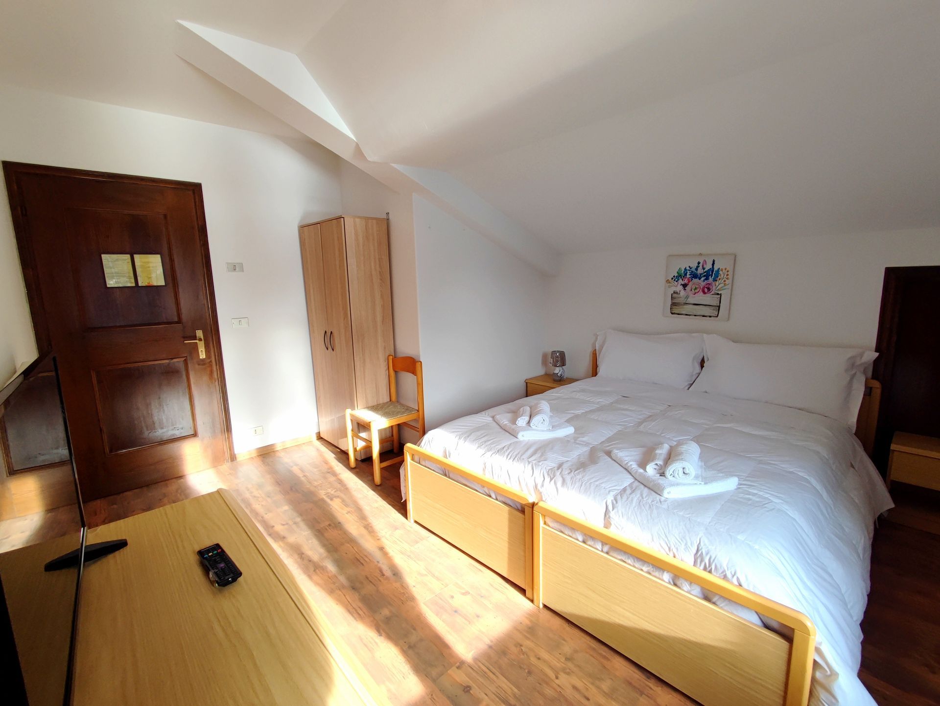 Camera da letto con biancheria bianca, mobili in legno e opere d'arte.