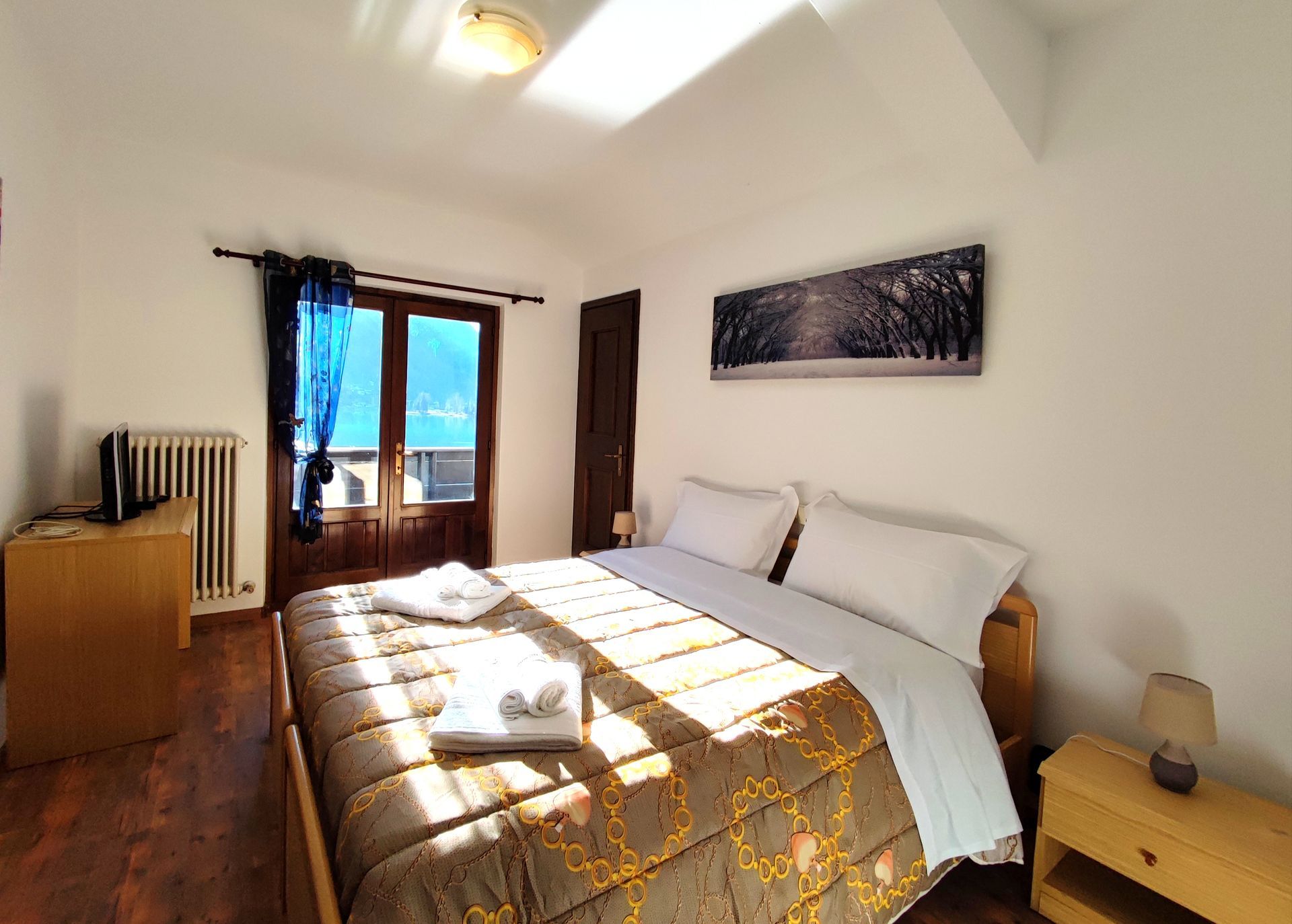 Camera da letto con letto matrimoniale, porte-finestre aperte e una piccola TV.