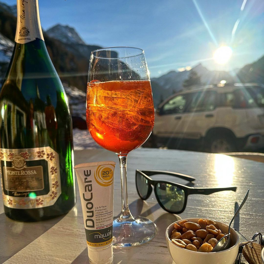 Aperol Spritz e snack su un patio soleggiato con vista sulle montagne; 
