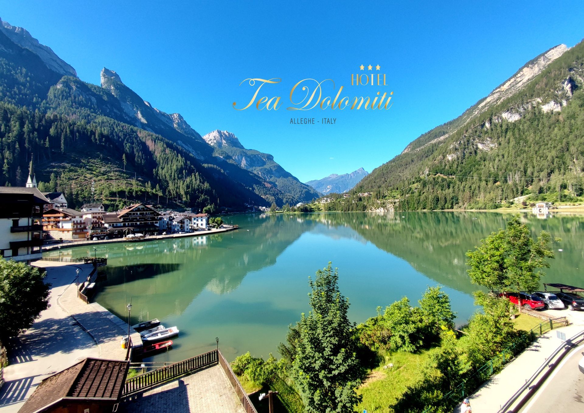 Vista sul lago delle Dolomiti, Italia. Le montagne incorniciano il calmo lago turchese, con un villaggio sulle sue rive.