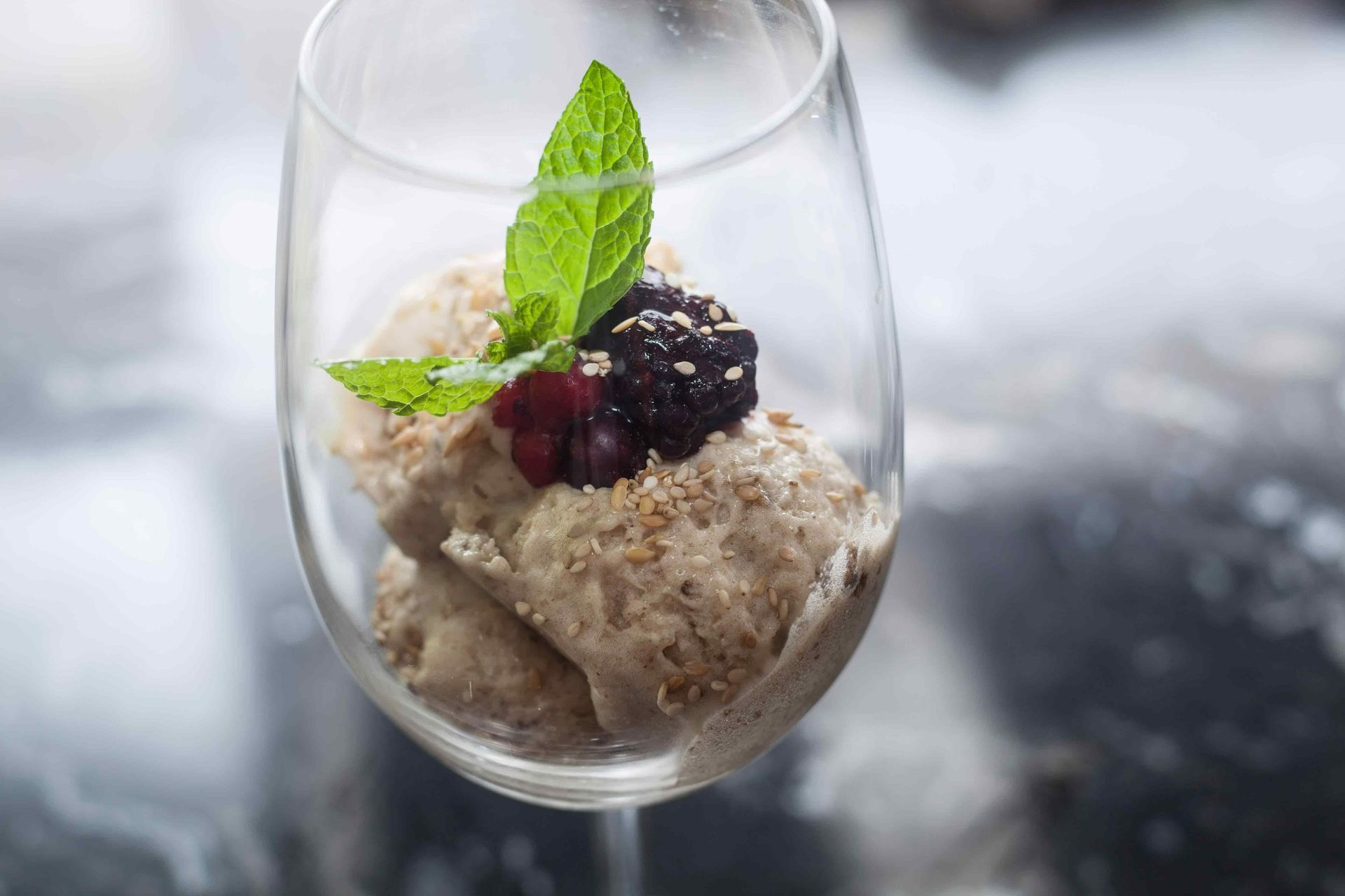Postre helado en copa de vino, adornado con menta y frutos rojos.