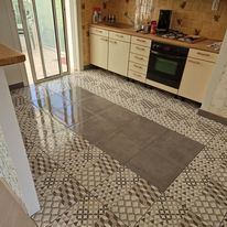 Cuisine avec sol à motifs, placards et cuisinière. Des portes coulissantes en verre donnent sur l'extérieur.