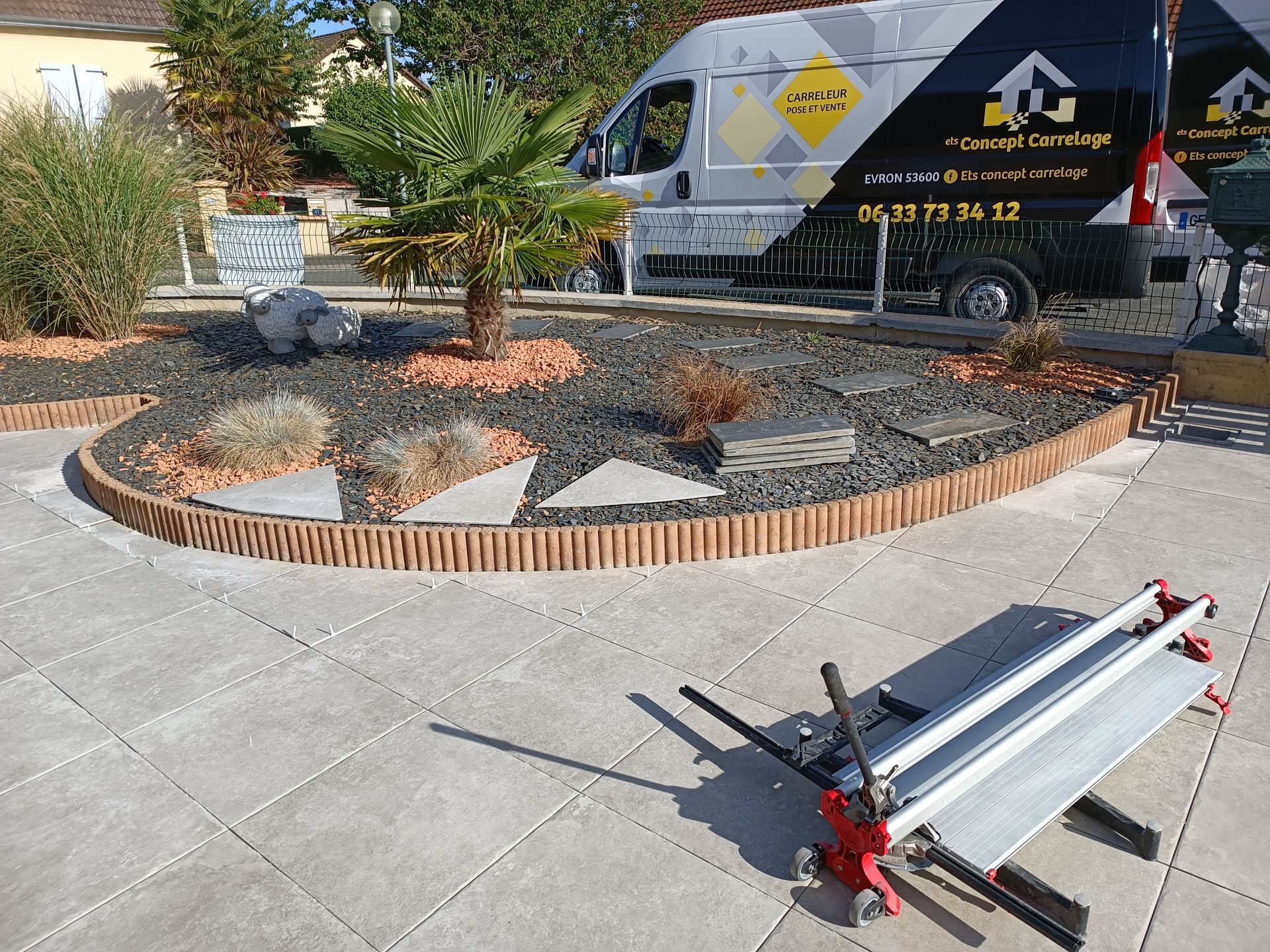 Projet d'aménagement paysager : pose de pavés, bordure, jardinière avec palmier, coupe-carreaux ; camionnette de chantier visible.