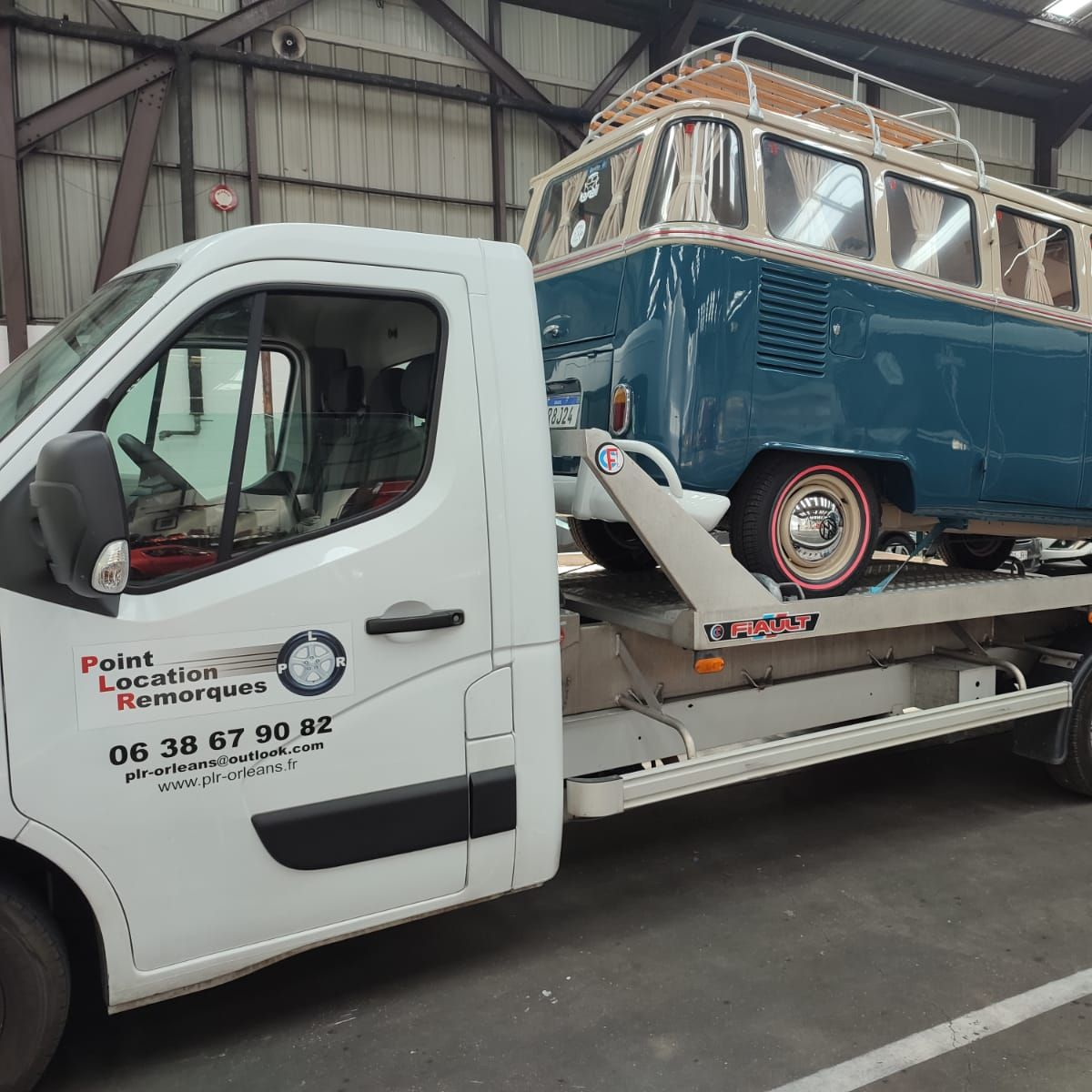 Une dépanneuse blanche portant une camionnette bleue.