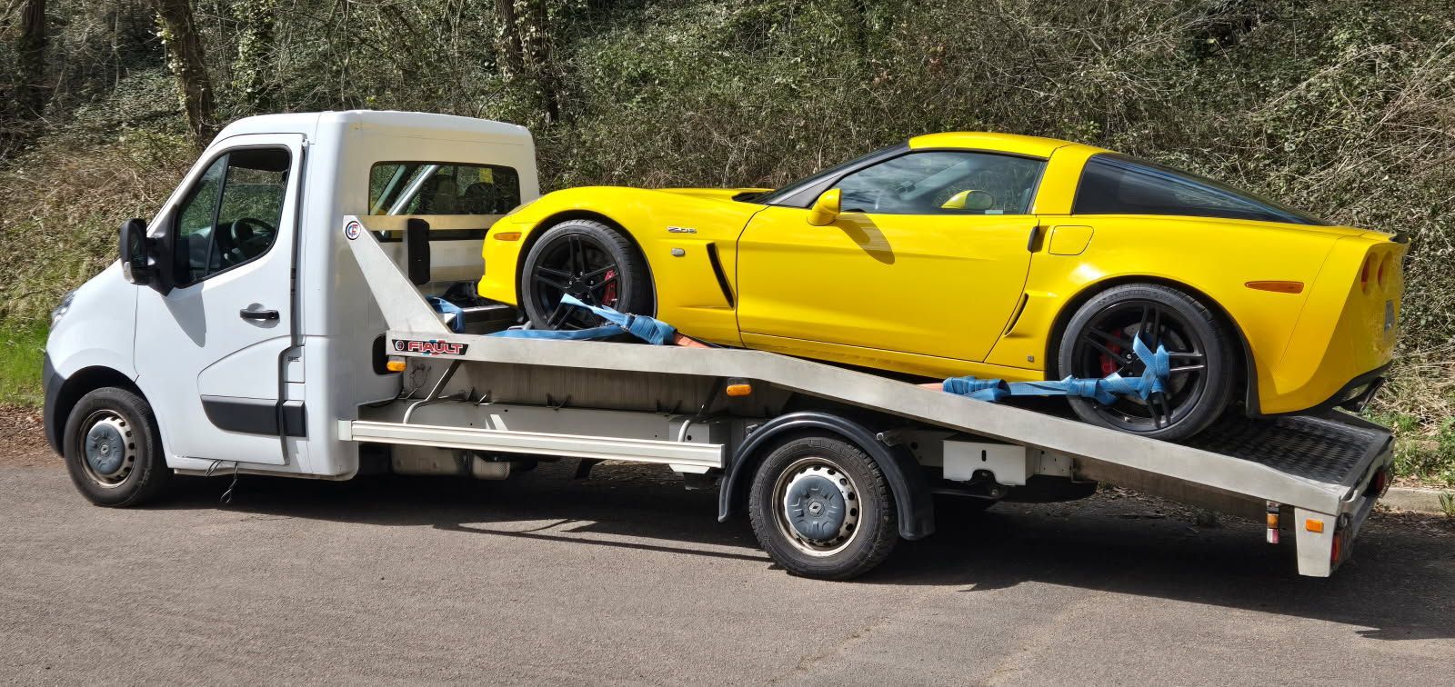 Une Corvette jaune est transportée sur une dépanneuse blanche.