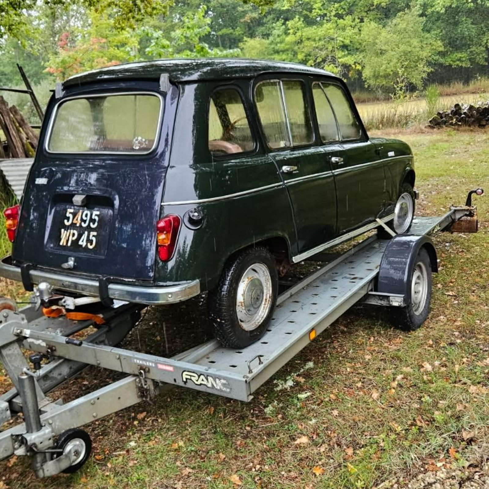 Une Renault 4 sur une remorque, garée sur l'herbe.