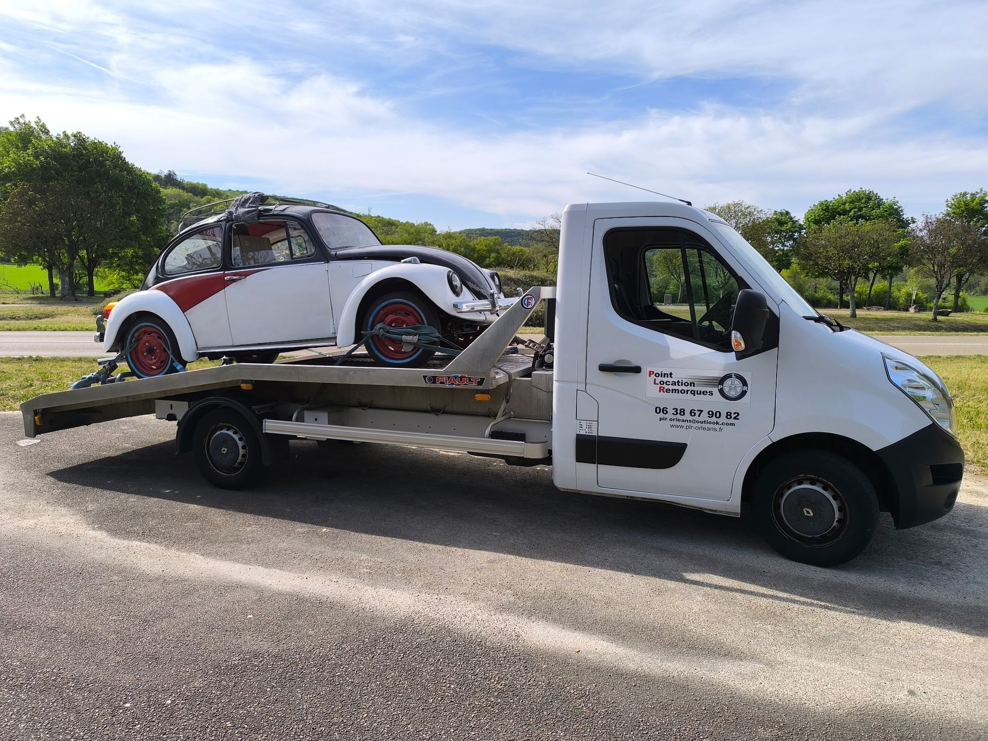 Une dépanneuse transportant une voiture de course blanche et rouge sur un plateau en bord de route