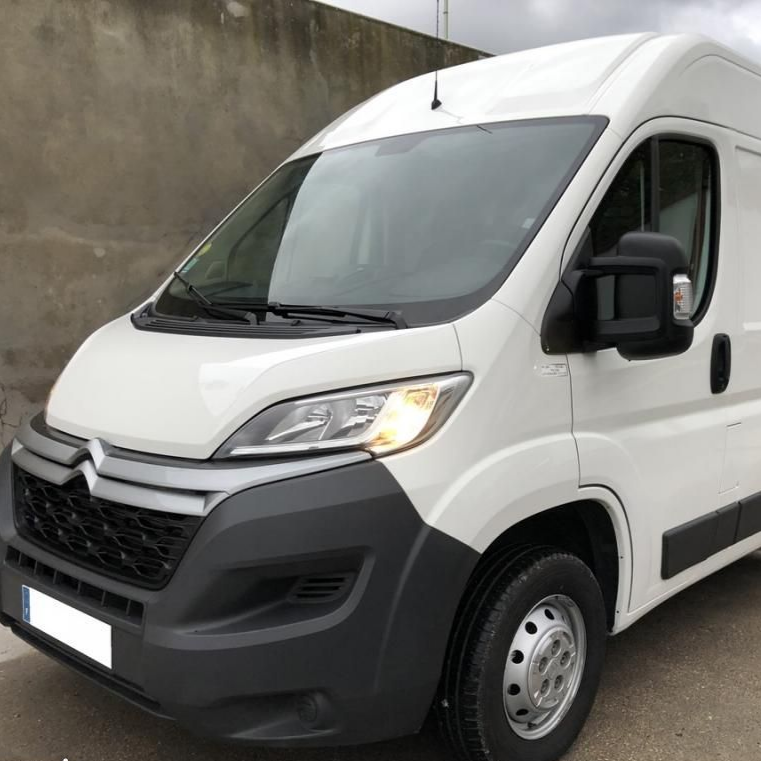 Fourgonnette utilitaire Citroën blanche avec calandre et pare-chocs noirs, garée à l'extérieur.