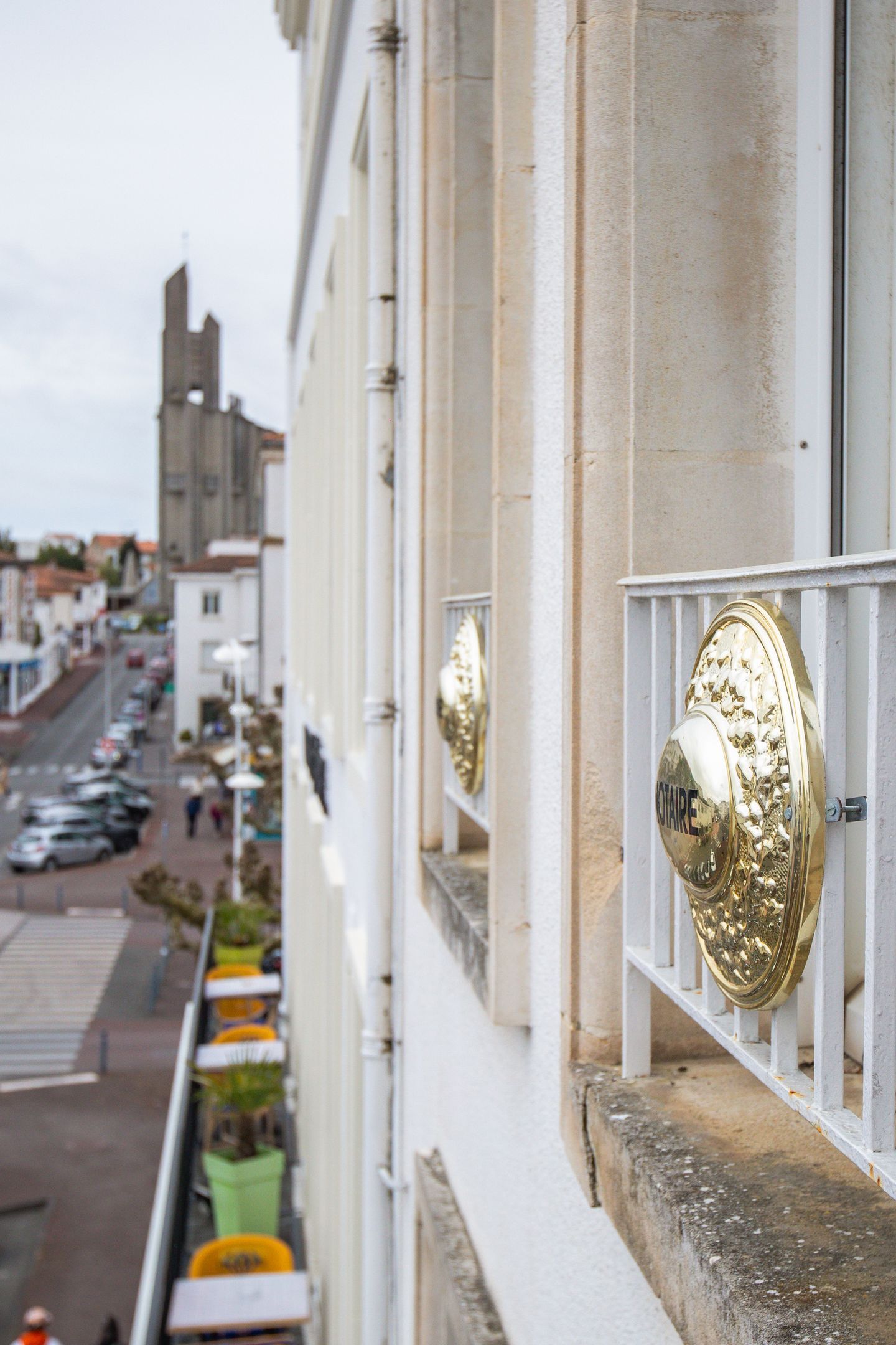 Une tablette graphique Wacom noire, munie d'un stylet vertical, est posée sur un bureau blanc sous une lampe de bureau en laiton à la lumière chaude, près d'une fenêtre.