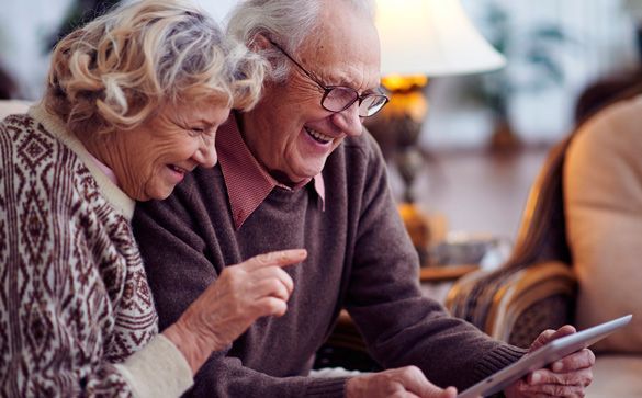 Una pareja de ancianos mira juntos una tableta.