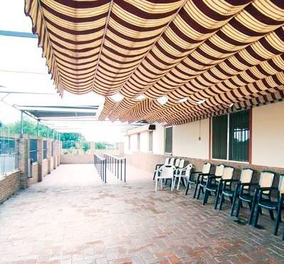 Un patio con sillas y mesas bajo un toldo de rayas.