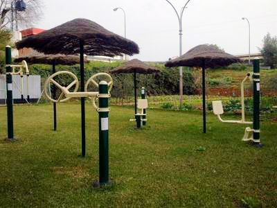 Un parque con sombrillas y aparatos de ejercicio en el césped.