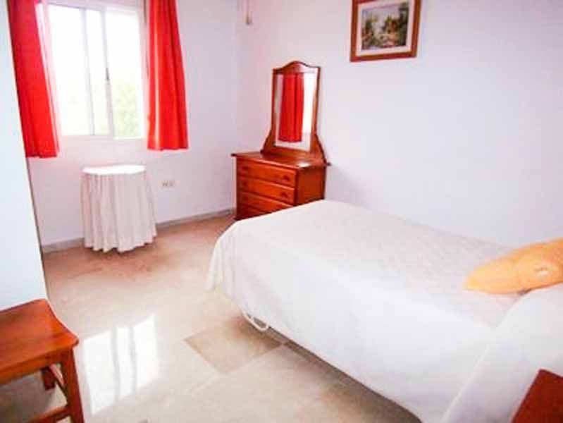 Un dormitorio con cama, cómoda, espejo y mesa.