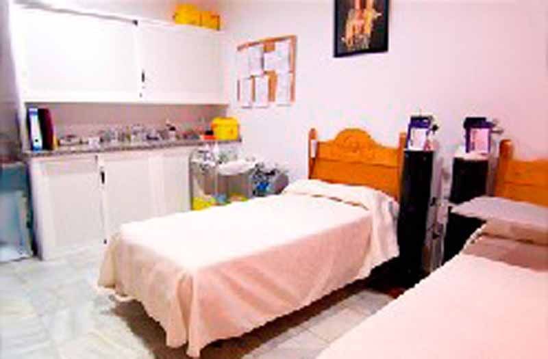 Un dormitorio con dos camas y una cocina al fondo.