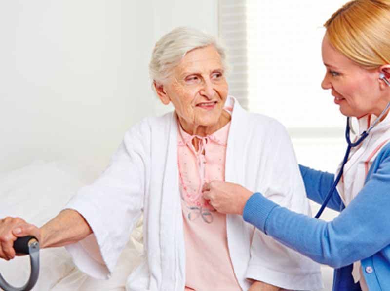 Una enfermera está escuchando los latidos del corazón de una mujer mayor con un estetoscopio.