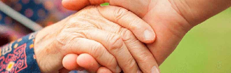 Un primer plano de una persona sosteniendo la mano de una persona mayor.