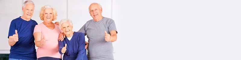 Un grupo de personas mayores están de pie uno al lado del otro y dan un pulgar hacia arriba.