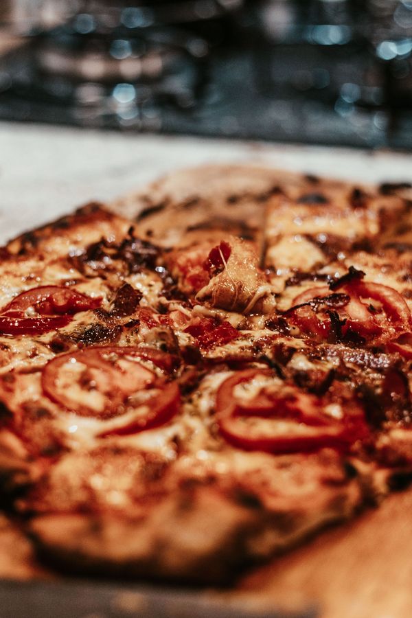 Gros plan d'une pizza pepperoni sur une planche en bois avec un arrière-plan flou.