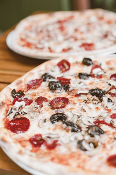 Deux pizzas garnies de champignons, de pepperoni et de fromage sur des assiettes blanches