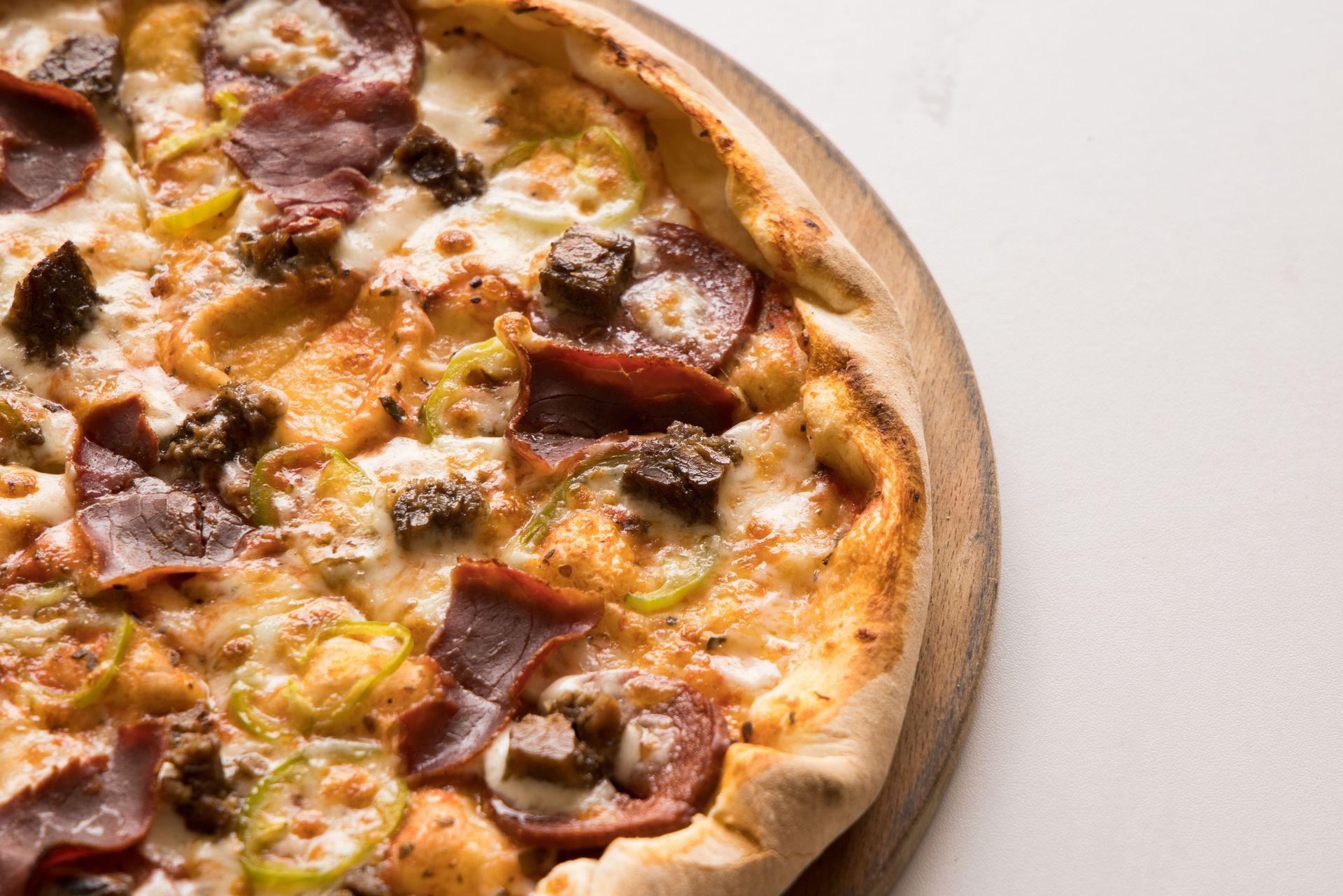 Pizza au fromage et à la viande tranchée sur une planche en bois sur fond blanc