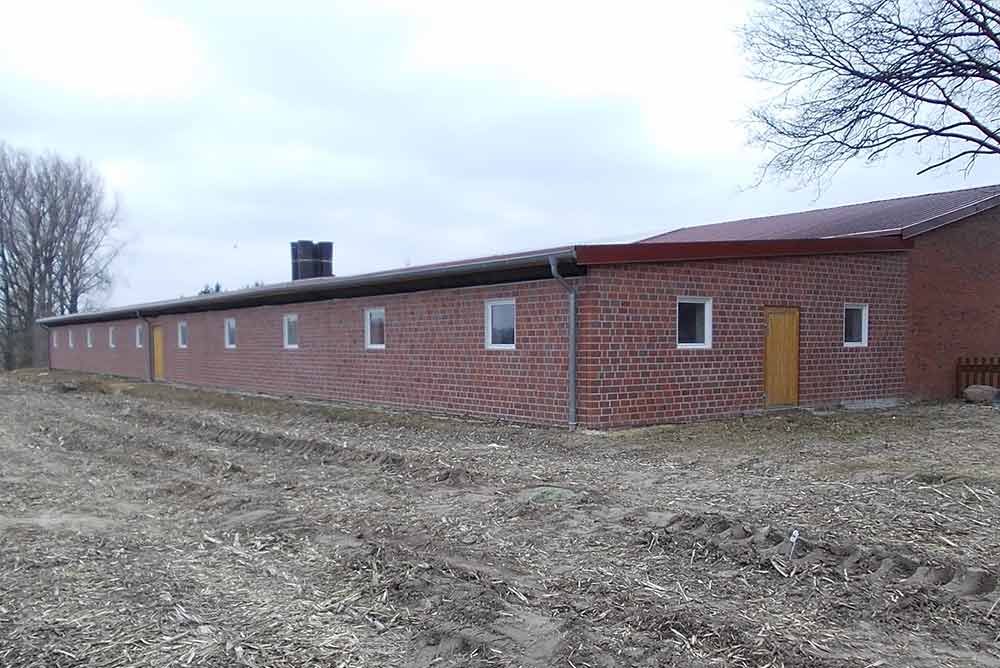 Ein großes Backsteingebäude steht inmitten eines Feldes.